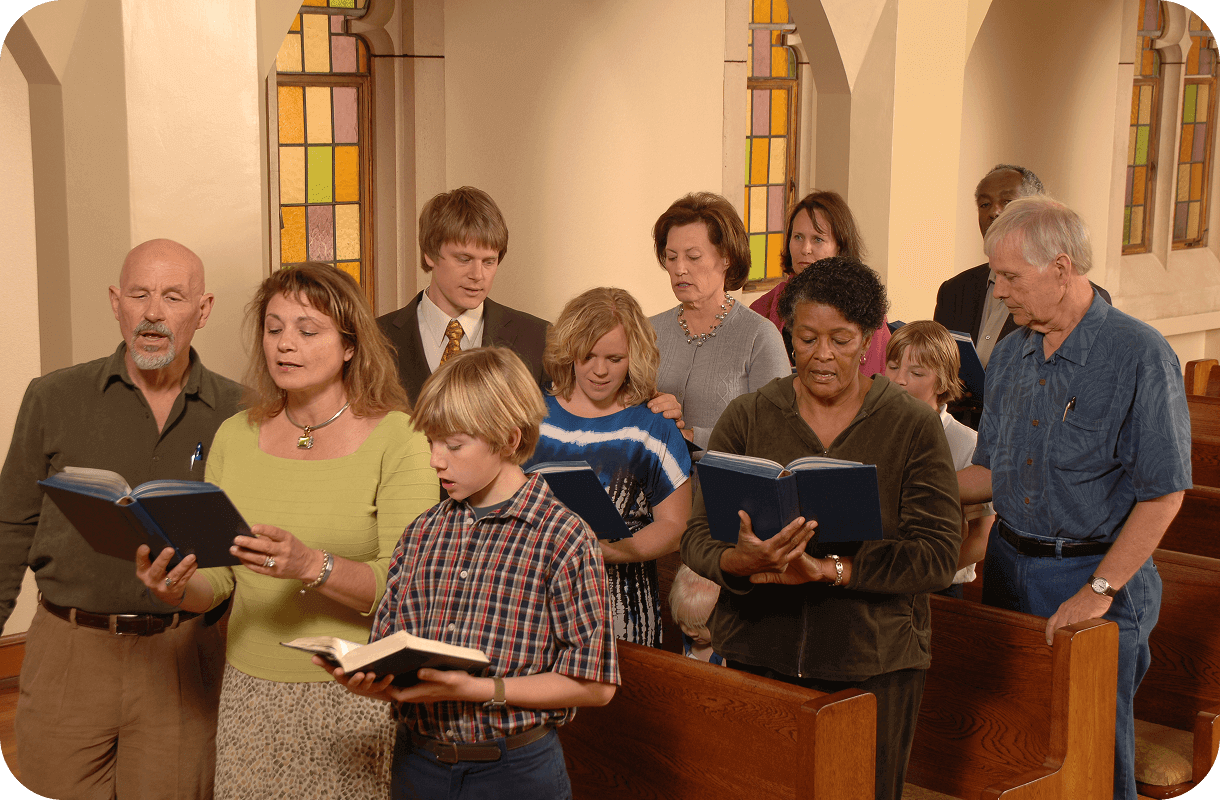 A diverse group of people stand in church pews, holding hymn books and singing—stained glass windows form a colorful backdrop. Some also engage in Bible memorization, deepening their understanding as they worship together.