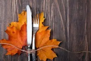 Autumn leaves with a knife and fork on a wooden table.