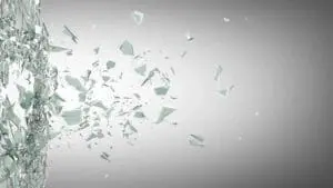 Glass shards shattering mid-air against a gray background.