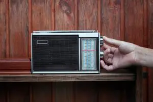 Hand tuning an old portable radio against a wooden background.