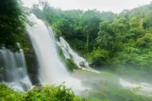 A large waterfall cascading through lush green forest.