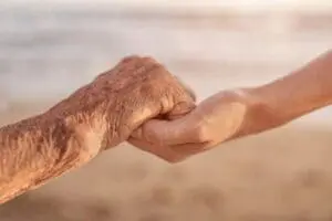 An elderly hand holding a younger hand symbolizing care and connection.