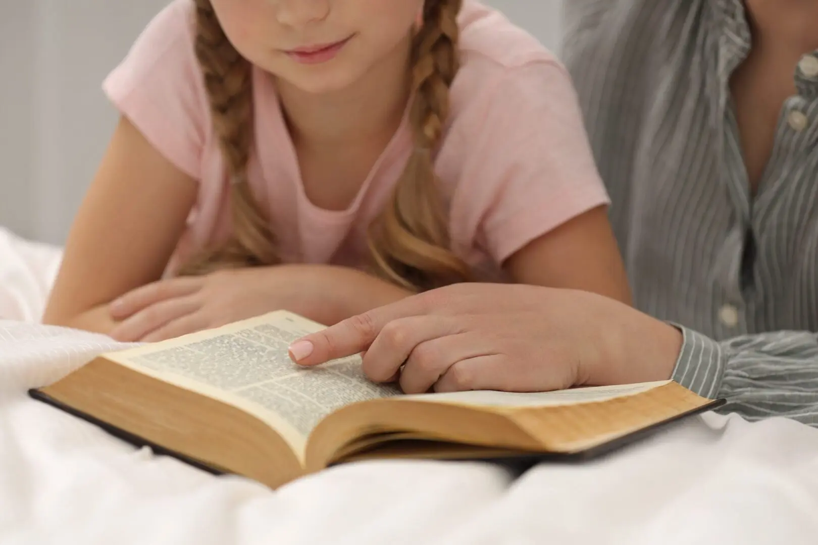 A child and an adult reading a book together.