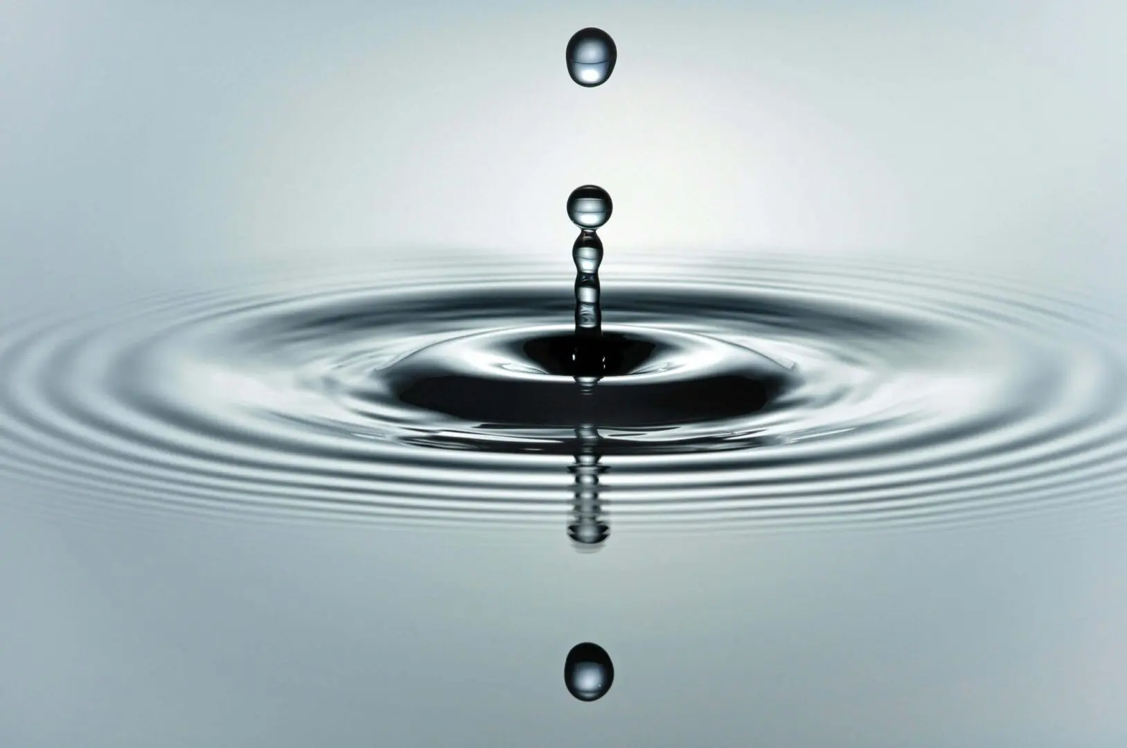 Droplets of water creating ripples on a calm surface.