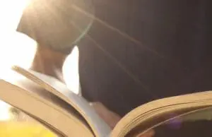 Person reading a book with sunlight streaming in.