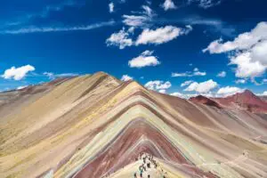 Rainbow Mountain's colorful striped slopes under a bright blue sky.