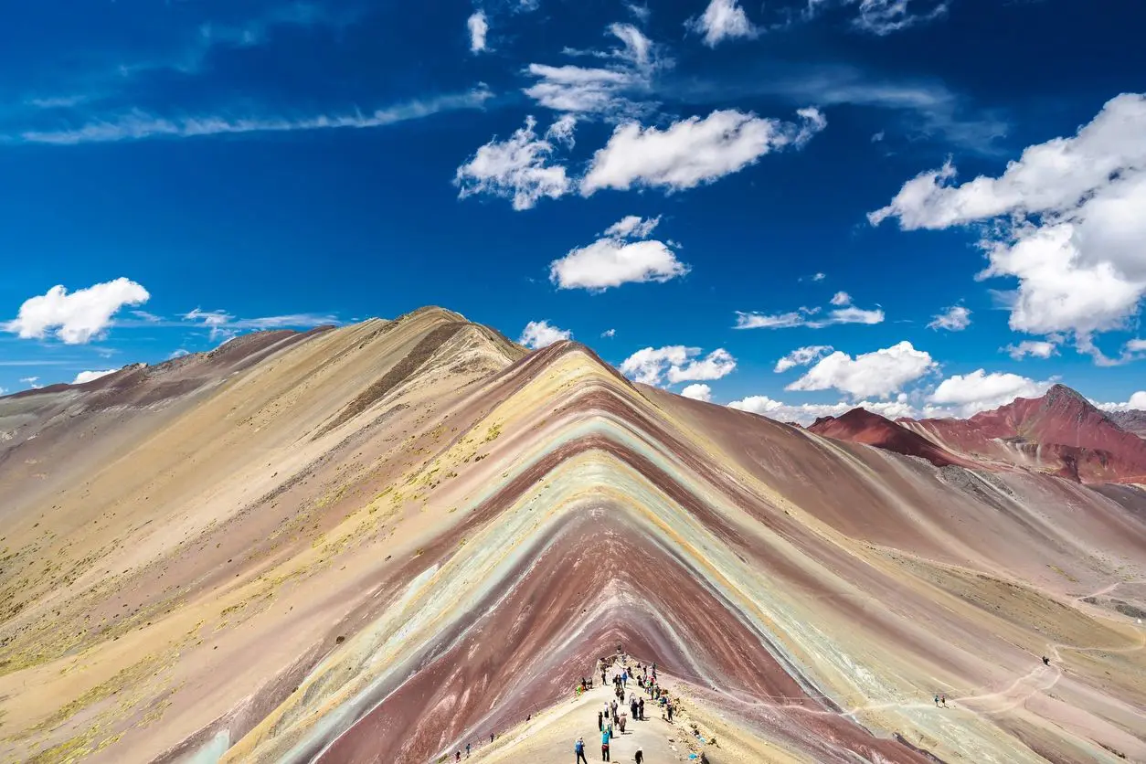 Rainbow Mountain's colorful striped slopes under a bright blue sky.