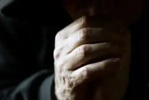 A close-up of an elderly hand with visible wrinkles and texture.