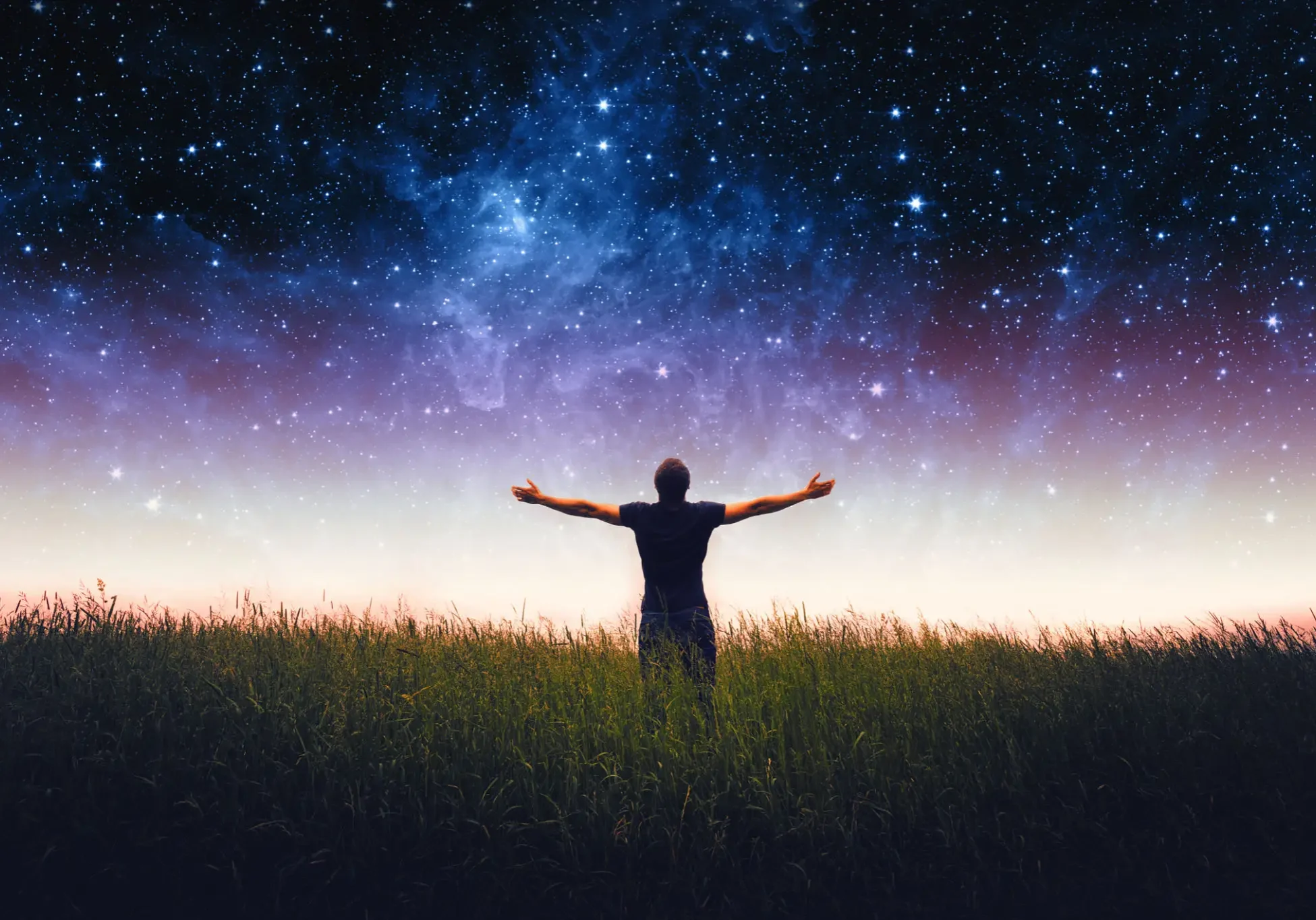 Person standing with arms open under a starry night sky.