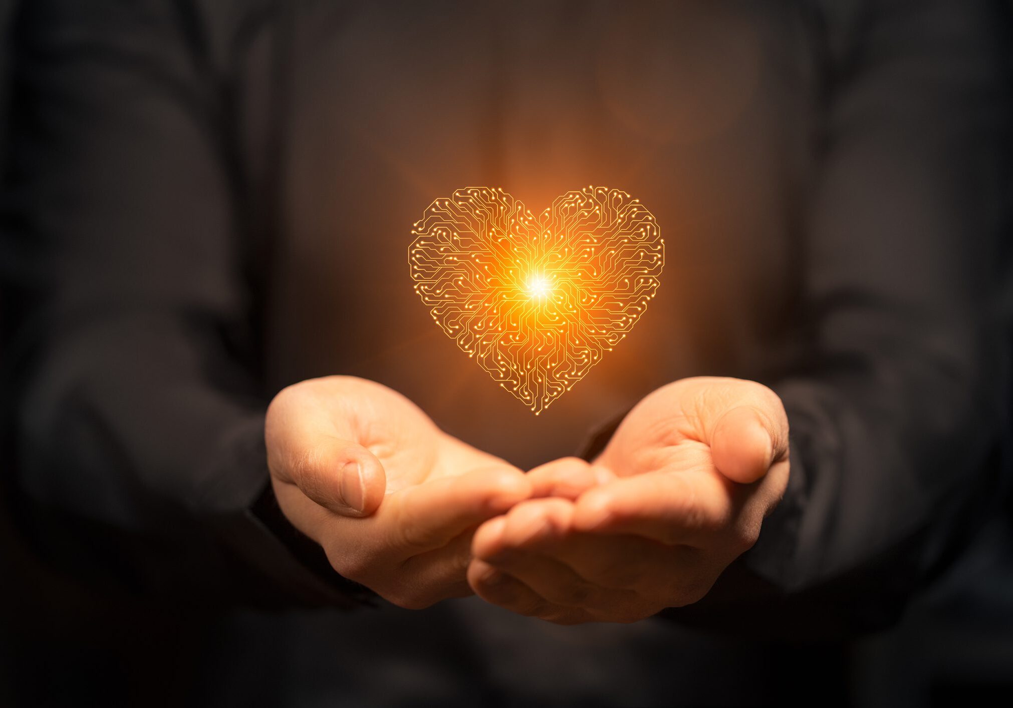 Hands holding a glowing heart made of light particles.