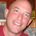 Smiling bald man indoors with wooden background.