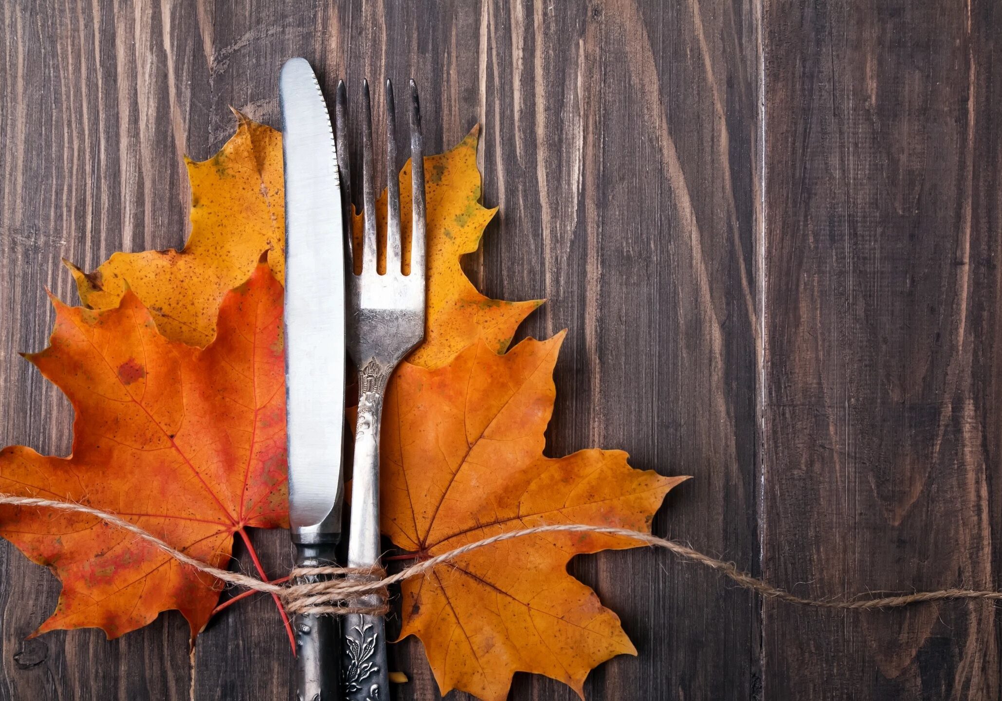 Autumn leaves with a knife and fork on a wooden table.