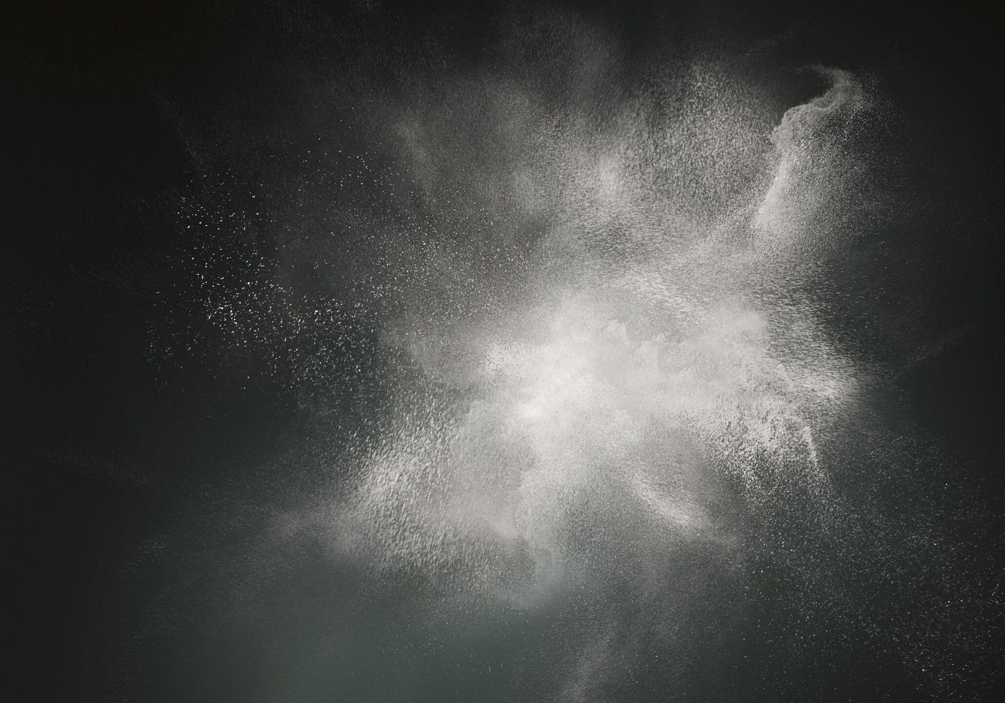 Abstract cloud of white powder or smoke against a dark background.