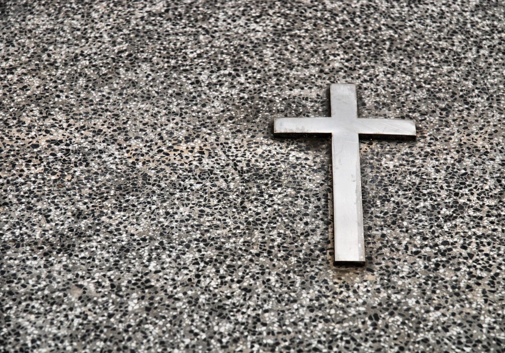 A silver cross on a speckled granite surface.